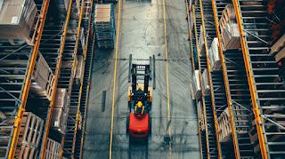 A forklift operator working with automated equipment in a modern warehouse.