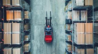 A forklift operator working with automated equipment in a modern warehouse.